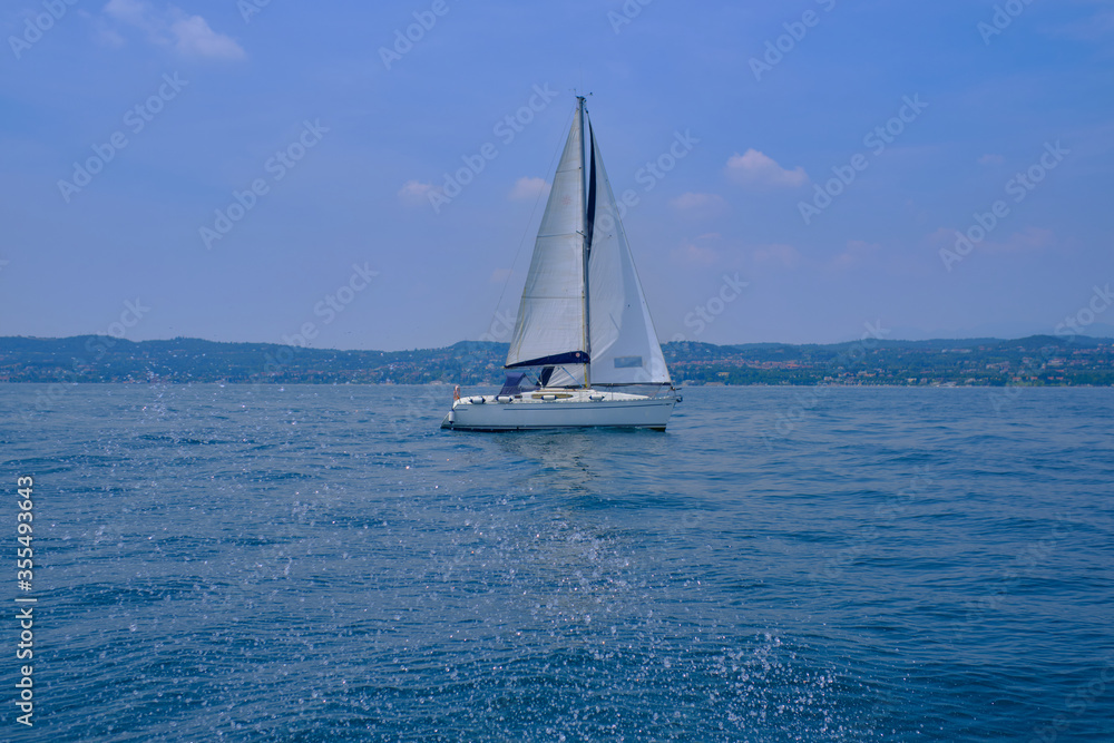 White yacht with a sail in motion, lake Garda