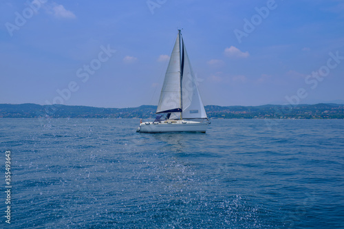 White yacht with a sail in motion, lake Garda