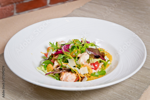 Delicious Caesar salad with prawns and Parmesan cheese. on a white plate.