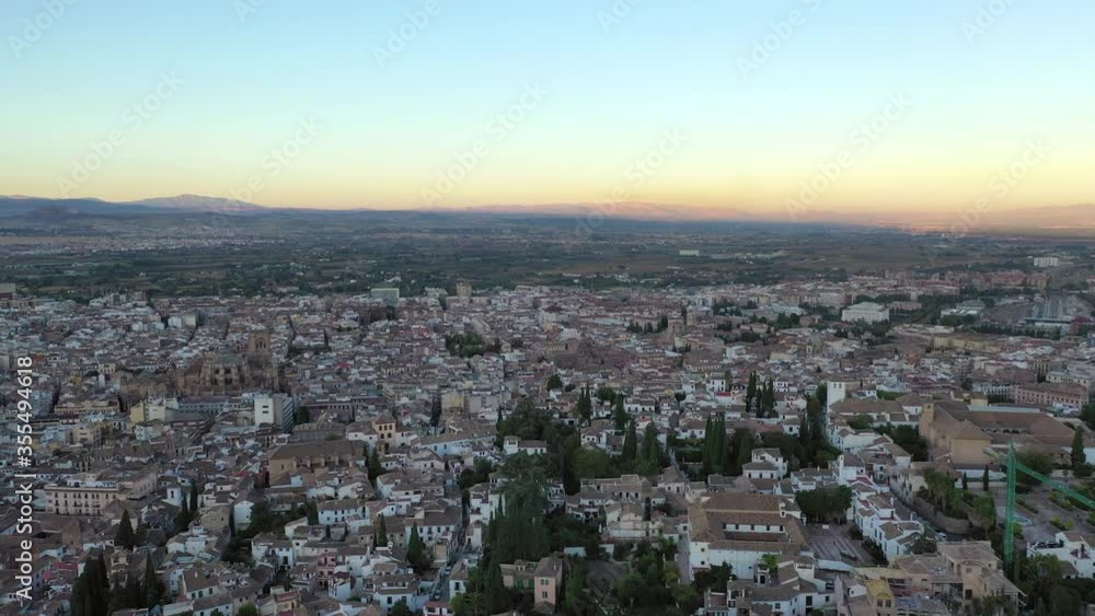 Aerial panning shot of cityscape against sky during sunset, drone flying over buildings in city - Granada, Spain Aerial panning shot of cityscape against sky during sunset, drone flying over buildings in city - Granada, Spain