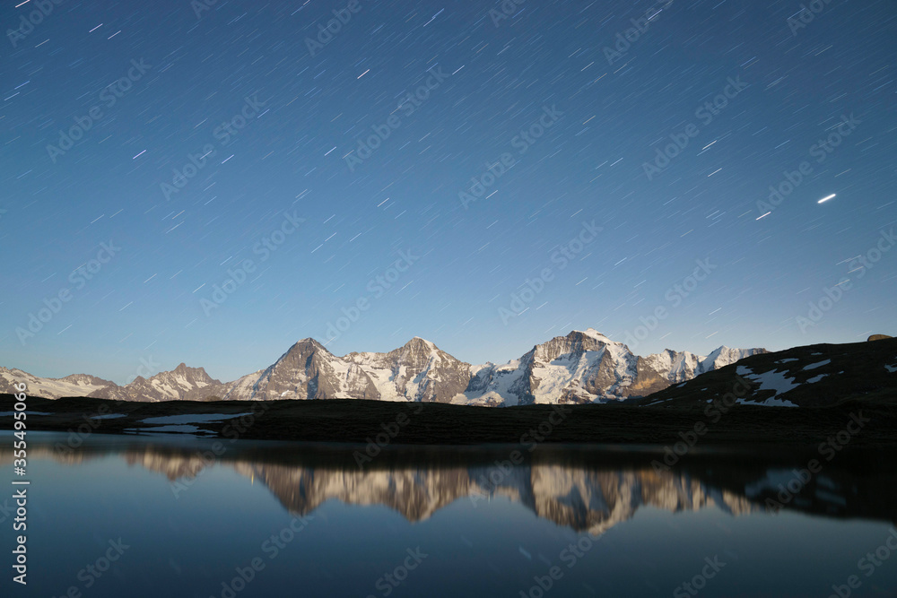 Langzeitbelichtung Eiger, Mönch und Jungfrau mit Bergsee und Sternenhimmel