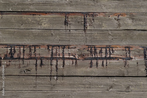 Oozed black pitch on on an old wooden door. Resin pocket on planks of wood of a fence.