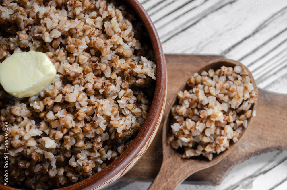 buckwheat porridge in a clay plate with butter and a wooden spoon buckwheat porridge in a clay plate with butter and a wooden spoon