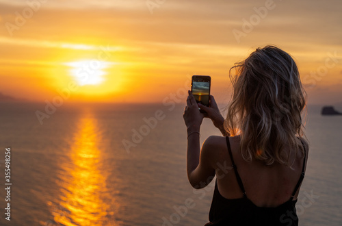 Foto Woman hands holding mobile phone at sunset