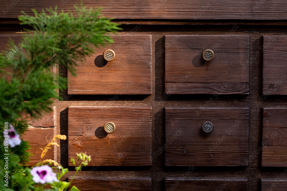Wooden chest of drawers with small drawers and round handles for storing dishes and menus in an outdoor cafe. Decorative element of the interior Wooden chest of drawers with small drawers and round handles for storing dishes and menus in an outdoor cafe. Decorative element of the interior