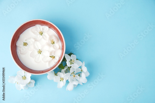 Milk of apple tree flowers on a blue background with copy space, the concept of natural cosmetics, aromatherapy, herbal medicine