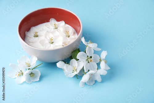 Milk of apple tree flowers on  blue background with copy space,  concept of natural cosmetics, aromatherapy