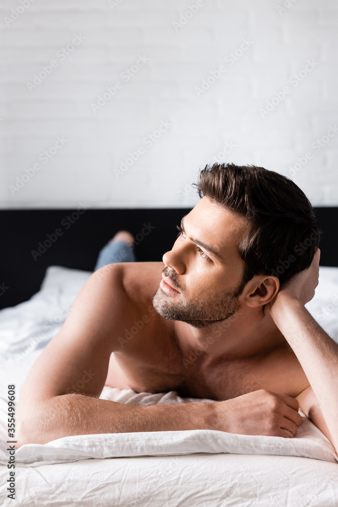handsome dreamy shirtless man relaxing on bed at home handsome dreamy shirtless man relaxing on bed at home