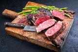 Gegrilltes dry aged Wagyu Rib-Eye Steak vom Rind mit grünen Spargel und Rotwein Salz as closeup auf einem alten rustikalen Holz Board 