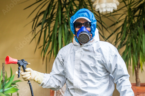 Portrait of a fumigator of phytosanitary and fungal products prepared to start fumigating and disinfecting a house. The worker is protected with an anti-contamination suit and mask