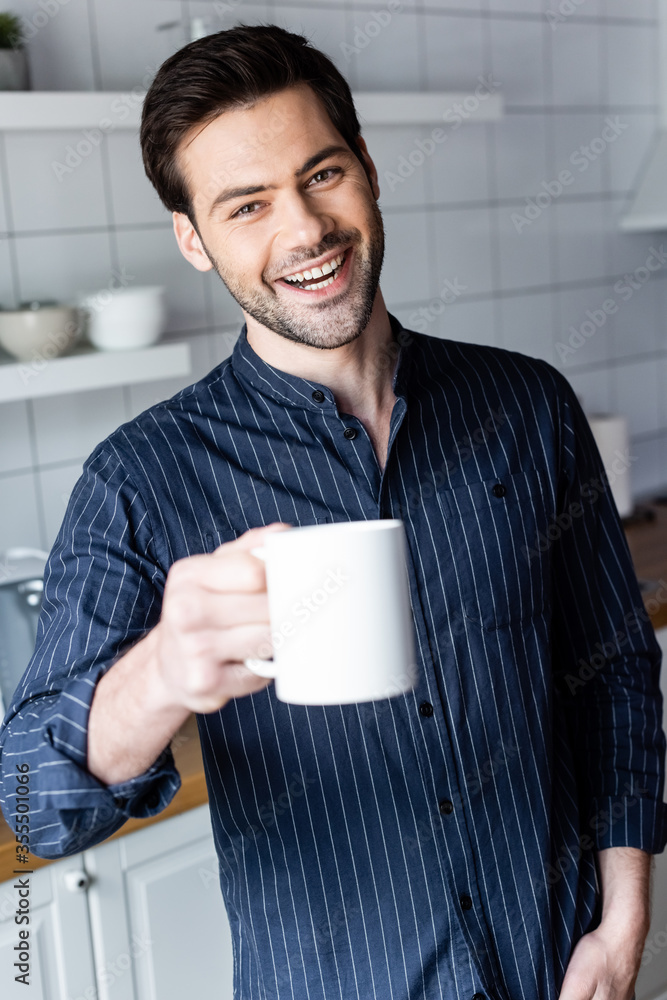 cheerful handsome man holding cup of coffee at home on quarantine cheerful handsome man holding cup of coffee at home on quarantine
