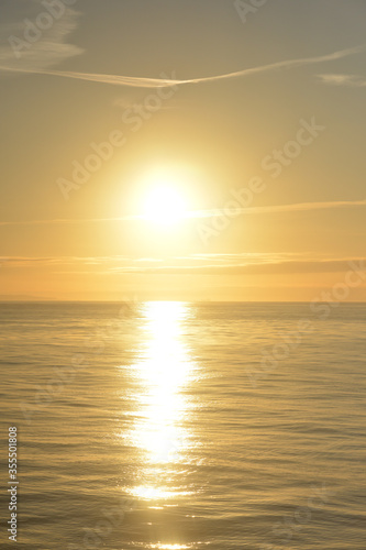 The sun sets  over the ocean in a golden haze a beautiful landscape taken from a cruise ship. © Eileen