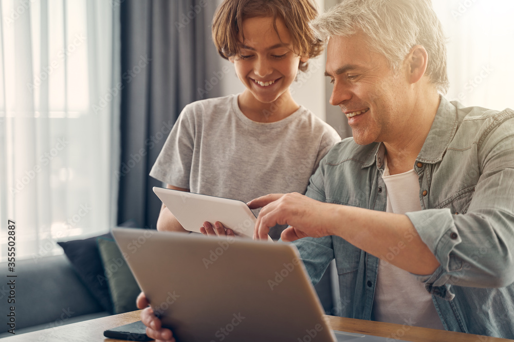 Smiling father and his son enjoying time together with gadget Smiling father and his son enjoying time together with gadget