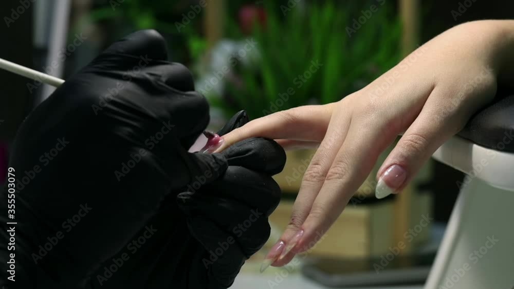 Professional manicure. Nail extension. Applying a drop of base Polish with a brush. Procedure for making long artificial gel nails in a modern beauty salon. Professional manicure. Nail extension. Applying a drop of base Polish with a brush. Procedure for making long artificial gel nails in a modern beauty salon.