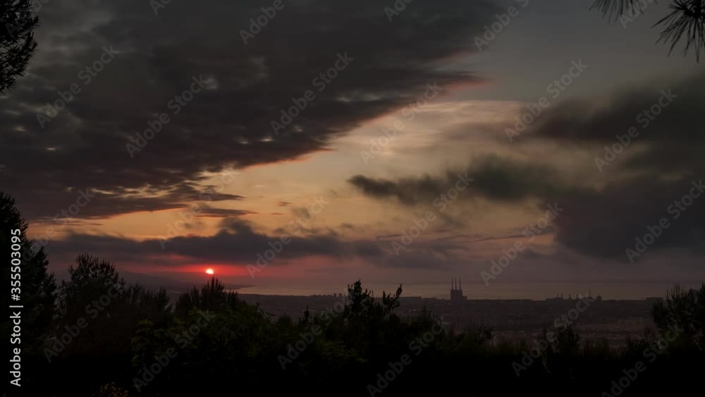Timelapse of sunrise above barcelona from guinardo park, with view of tres xemeneies and cloudy sky on a summer morning Timelapse of sunrise above barcelona from guinardo park, with view of tres xemeneies and cloudy sky on a summer morning
