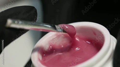 Professional manicure. Nail extension. Typing with a brush from a jar of the nail coating base. Procedure for making long artificial gel nails in a modern beauty salon.