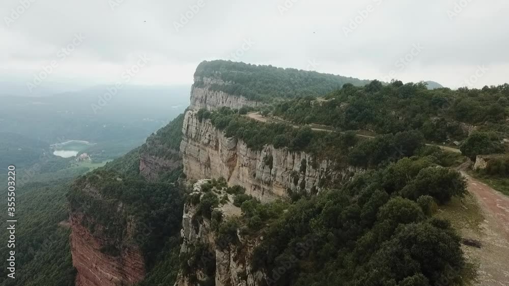 Aerial shot of rocky mountain cliff with plants against sky, drone flying by over natural landscape - Tavertet, Spain Aerial shot of rocky mountain cliff with plants against sky, drone flying by over natural landscape - Tavertet, Spain