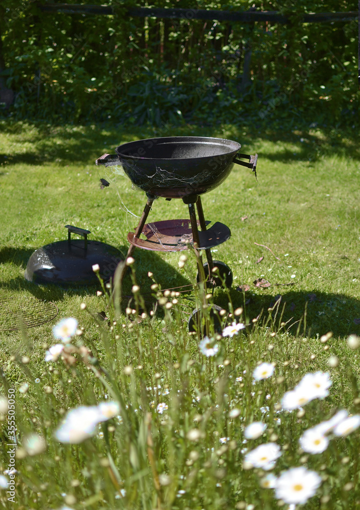 old barbecue grill with spider webs standing on the grass old barbecue grill with spider webs standing on the grass