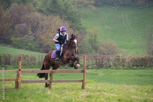 Up and over they go. Young rider and her horse jumping wooden jumper during a cross country event they are competing in 