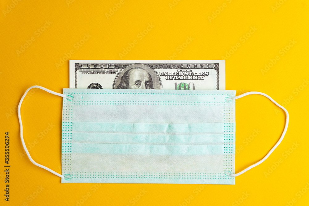 The medical mask covers the banknote. Concepts of protecting the currency and economy during the crisis. The medical mask covers the banknote. Concepts of protecting the currency and economy during the crisis.