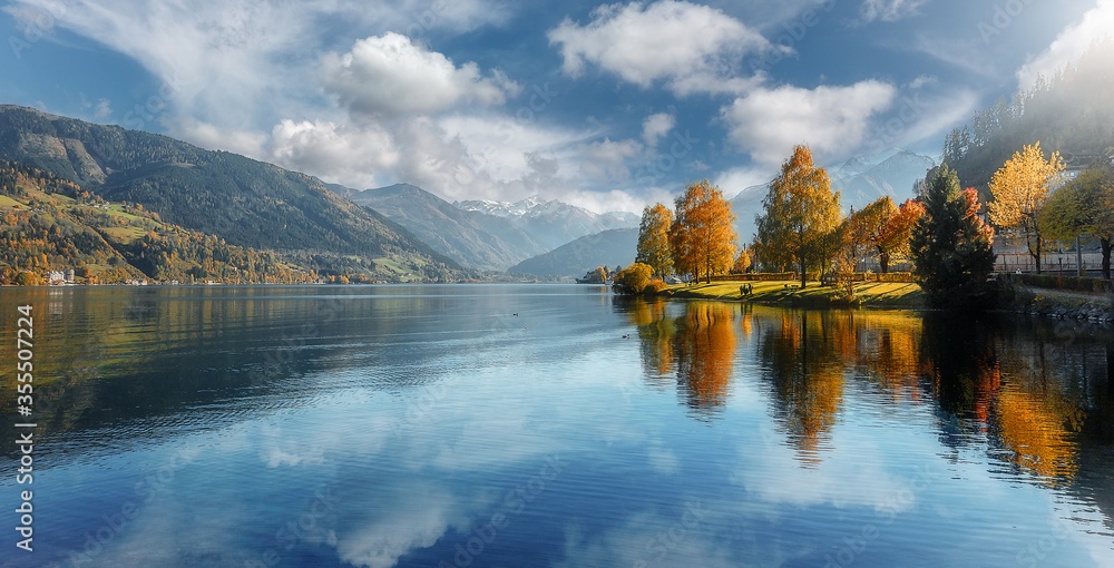 Beautiful Sunny day in Alps. wonderlust view of highland lake With autumn trees under sunlight and perfect sky. Landscape with Alps and Zeller See in Zell am See, Salzburger Land, Austria