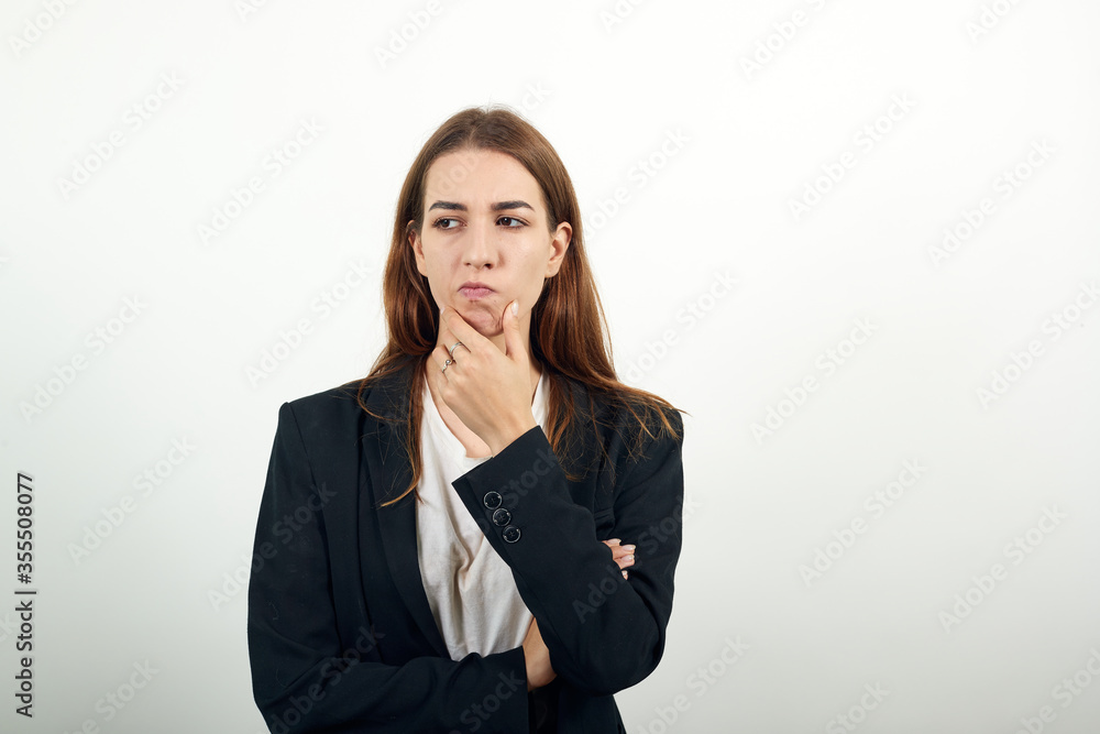 Hand on chin thinking about question, pensive expression. Doubt. Thoughtful face. Using that incredibly sharp business mind. Young attractive woman with brown hair in a light t-shirt and black jacket Hand on chin thinking about question, pensive expression. Doubt. Thoughtful face. Using that incredibly sharp business mind. Young attractive woman with brown hair in a light t-shirt and black jacket