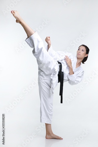 Black belt martial artist woman doing a high kick in her karate clothes. 