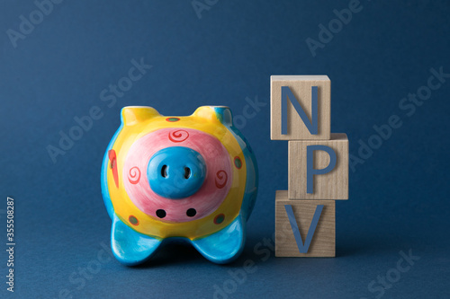 NPV (net present value) acronym on wooden cubes on a blue background. Business concept