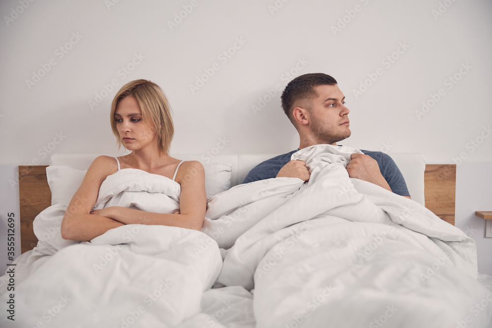 Young attractive couple staying in bed looking sad Young attractive couple staying in bed looking sad