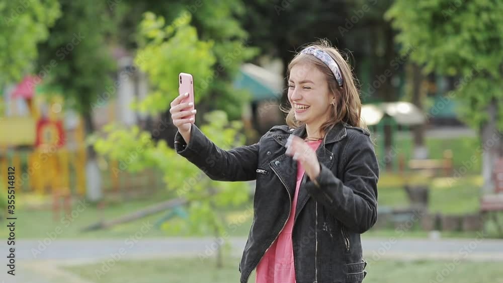 Beautiful young girl with dark curly hair using her cell phone, outdoor. The blogger girl is broadcasting. Beautiful young girl with dark curly hair using her cell phone, outdoor. The blogger girl is broadcasting.
