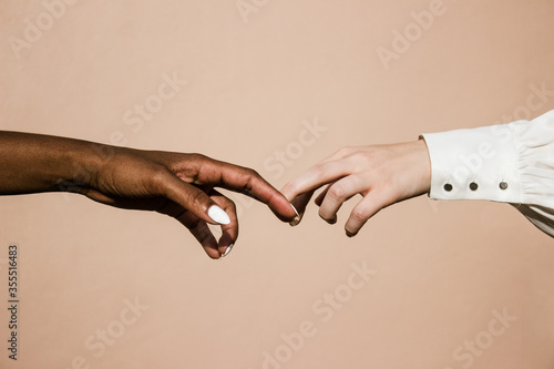 white and black hands reaching towards each other 
