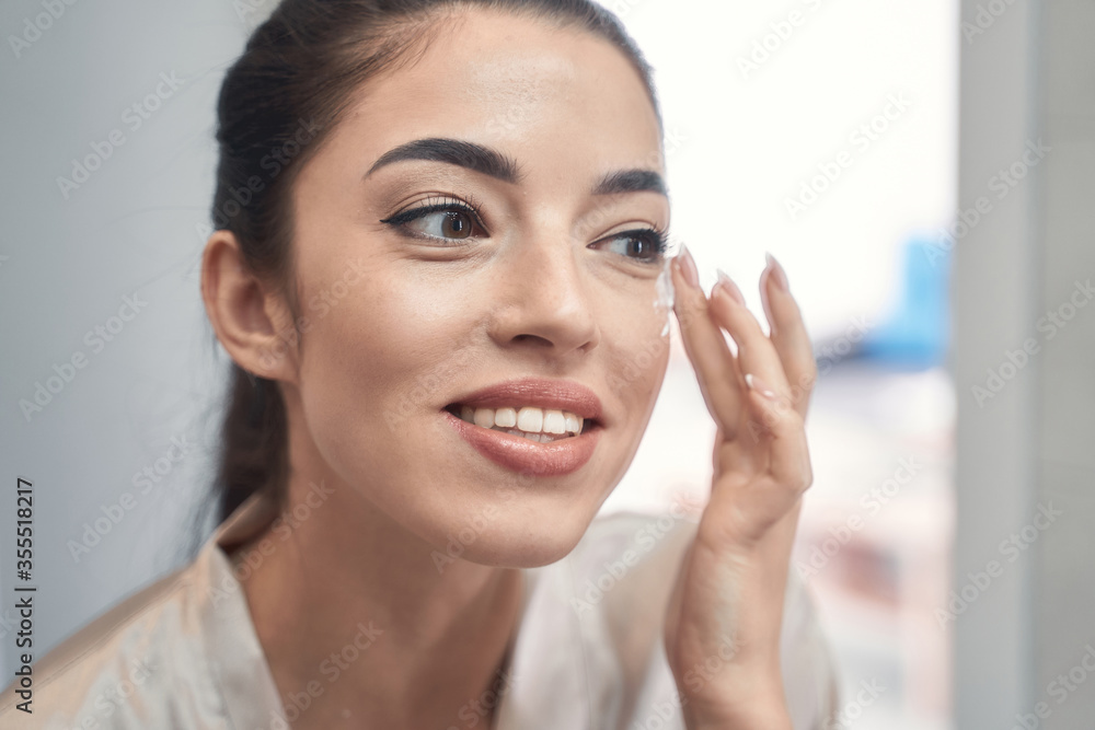 Adorable young model using moisturizer in the morning Adorable young model using moisturizer in the morning