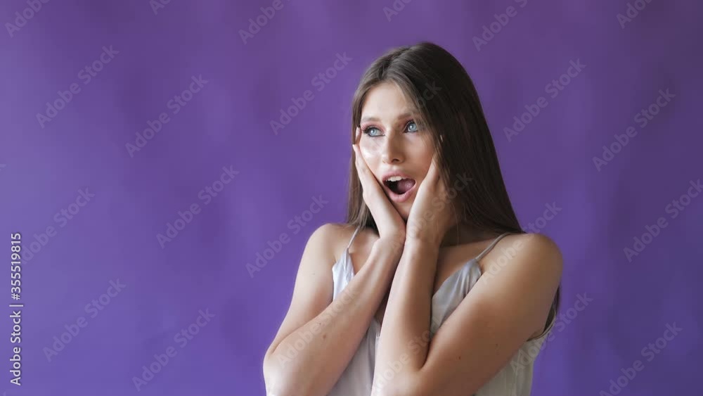 A young beautiful girl shows emotions in the Studio on a purple background. Girls for advertising A young beautiful girl shows emotions in the Studio on a purple background. Girls for advertising