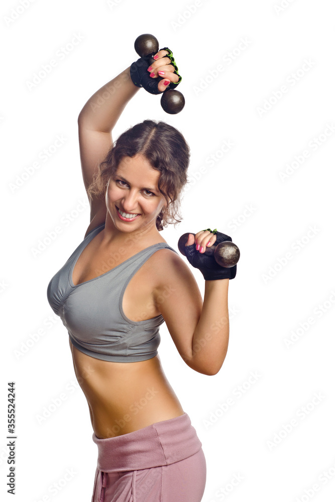 Obraz premium Beautiful emotional woman or girl with her hair loose, plays sports in sportswear and gloves with dumbbells in her hands, on a white isolation background.