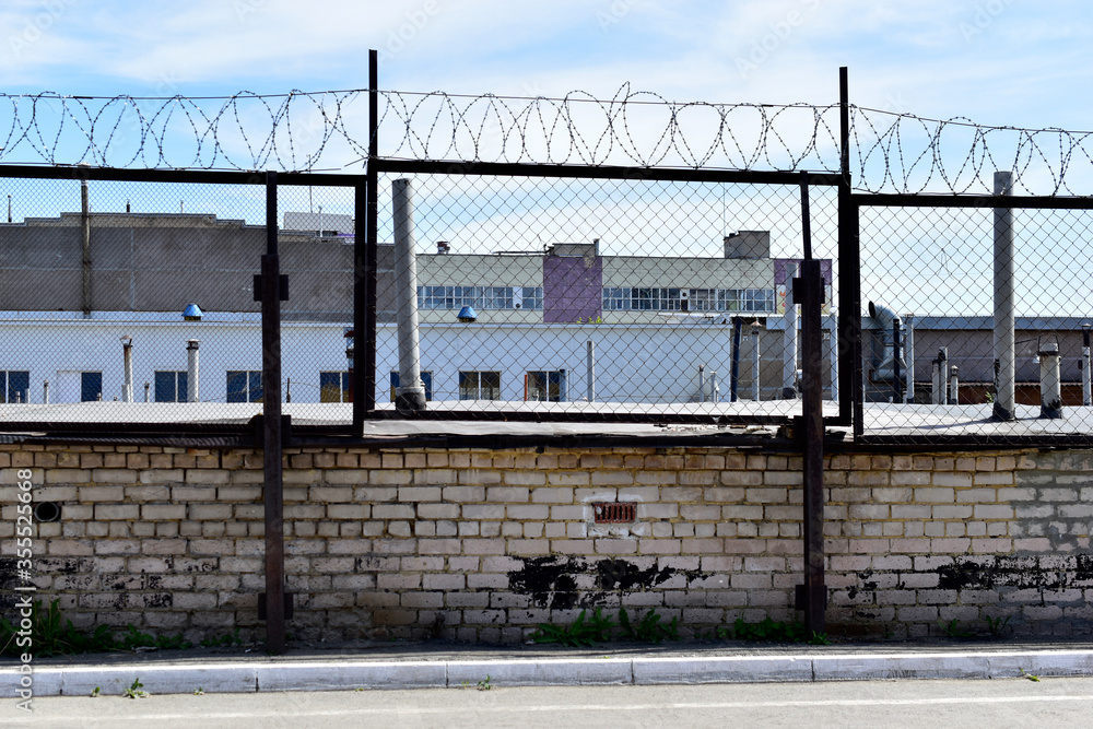 Fototapeta premium Factory zone barbed wire fence and buildings