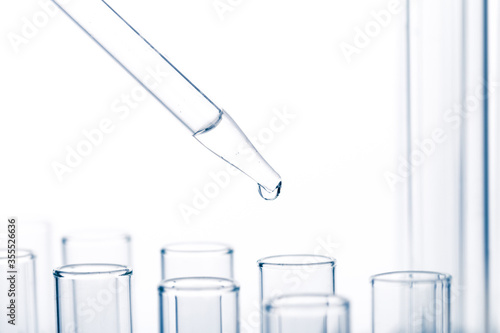 pipette with a drop and scientific laboratory test tubes in a research laboratory.