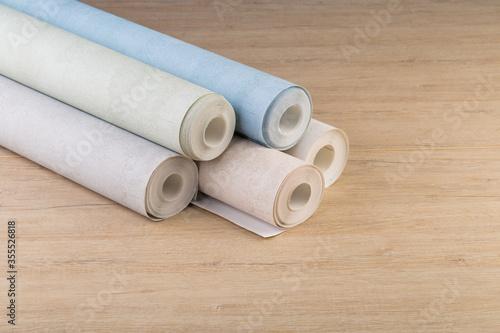 rolls of multi-colored paper wallpaper on a wooden table