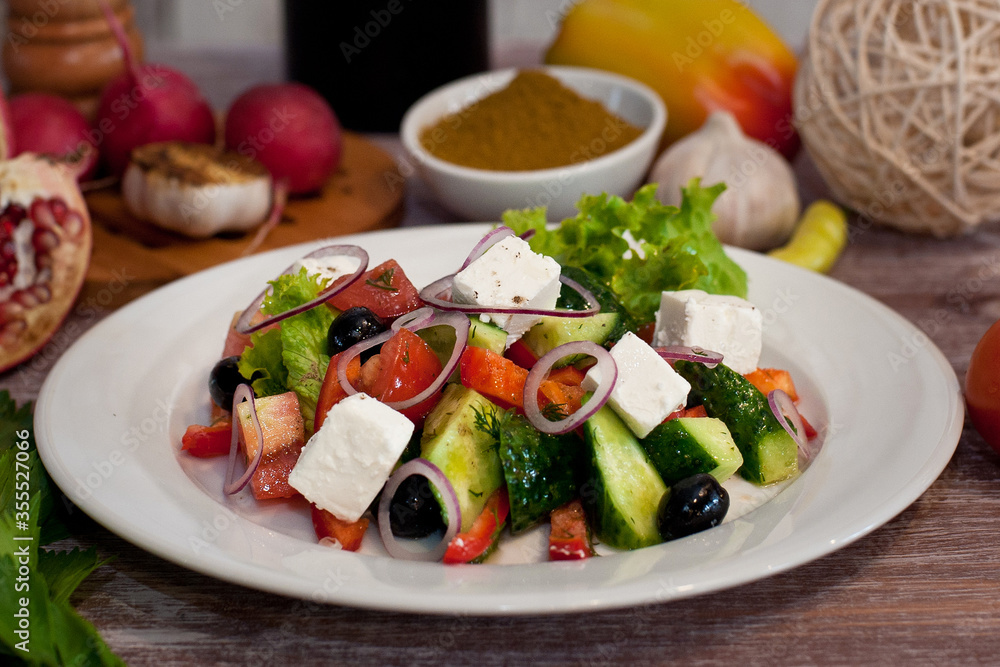 Greek salad on a white plate. Good nutrition. National cuisine. Salad with cucumbers, tomatoes, feta cheese, olives and herbs