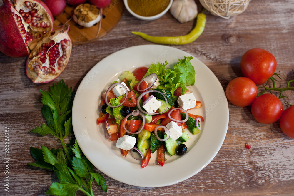 Greek salad on a white plate. Good nutrition. National cuisine. Salad with cucumbers, tomatoes, feta cheese, olives and herbs