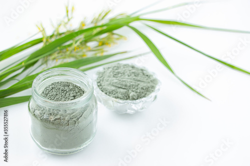 Foto Green cosmetic clay for face and hair care in a glass jar on a white background