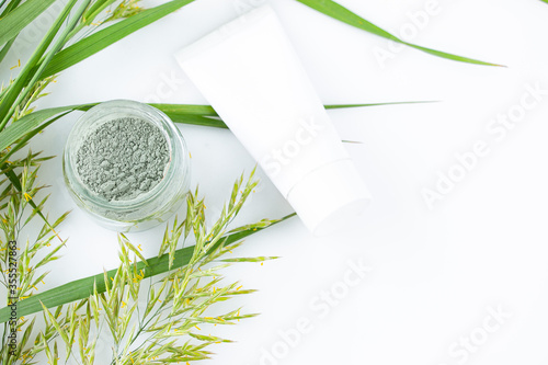 Green clay powder in a glass jar - for face and body skin care - on a white background  top view. Spa and body care concept. Flatlay.