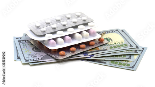 Pills in blisters on dollar bills on a white isolated background