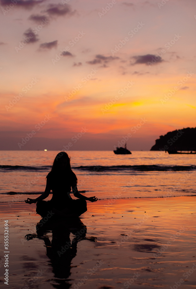 Fototapeta premium Evening yoga on the beach. Young girl practices yoga.