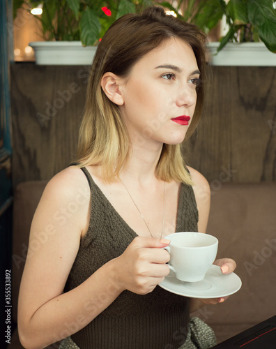 cute girl with blond hair drink coffee or tea n cafe