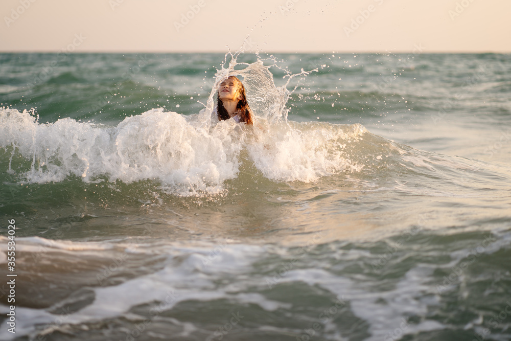 teenager girl in dress swims in sea with high waves. entertainment in vacation. teenager girl in dress swims in sea with high waves. entertainment in vacation.
