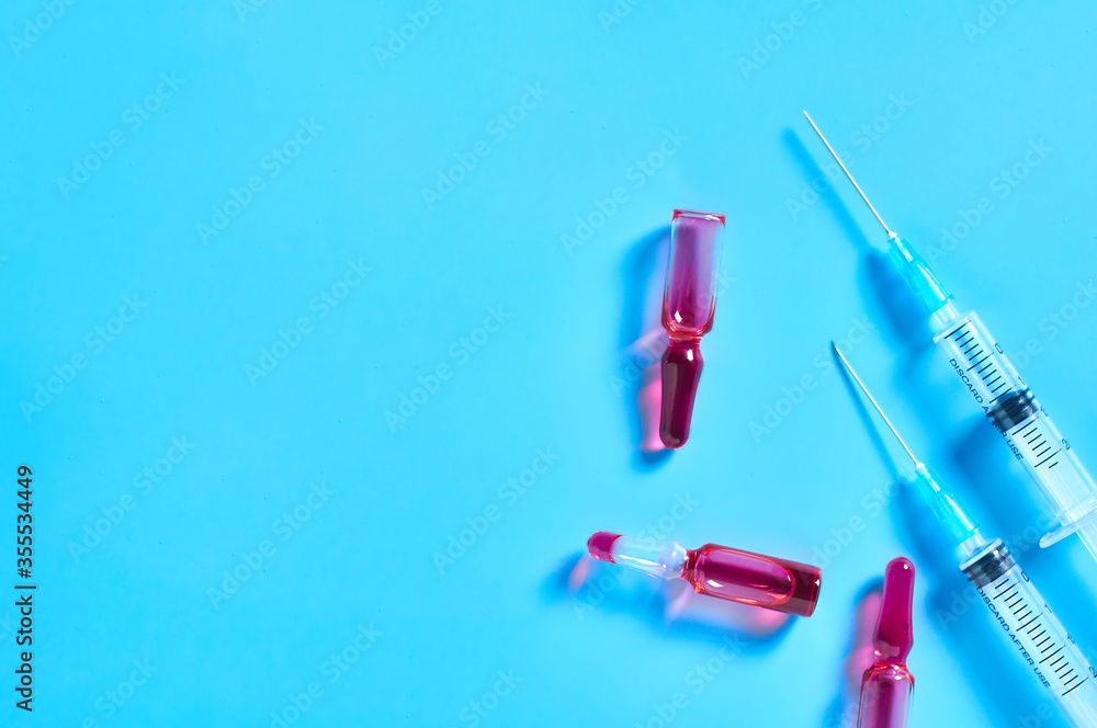 Disposable syringes and red vaccine on blue background. Healthcare and medical concept Disposable syringes and red vaccine on blue background. Healthcare and medical concept