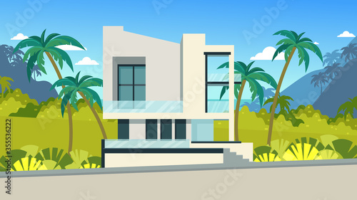 Modern house in the tropical strip. Rest and rental housing on vacation. White house with large windows, a terrace. Tropical plants on the lawn of the house.
