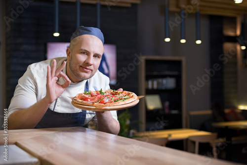 Kitchen restaurant, pizzeria chef stands in the workplace. Looking at camera, Copy space for text