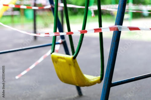 Wall Mural Yellow metal children's swing on a sports playground in the park wrapped with red barrier tape