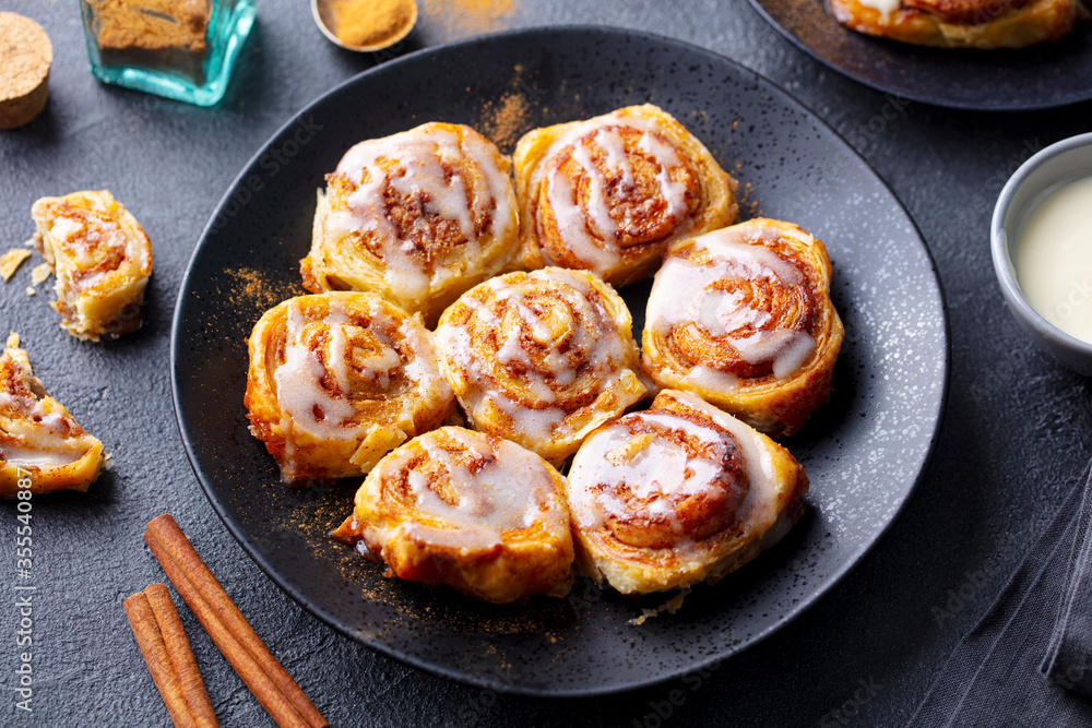 Cinnamon rolls, buns on black plate. Dark background. Close up. Cinnamon rolls, buns on black plate. Dark background. Close up.